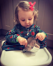 Load image into Gallery viewer, A baby girl is maneuvering her spoon scooping yogurt from a stainless steel bowl