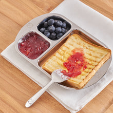 Load image into Gallery viewer, Shiny stainless steel baby divided plate that fits one whole toast and couple of side dishes. The food pusher or butter speader is used to spread strawberry jam.